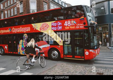 KOPENHAGEN, DÄNEMARK - 14. AUGUST 2021: Radfahrerin hielt neben der Stadtrundfahrt Hop-on-Hop-off-Bus in der Innenstadt von Kopenhagen Stockfoto