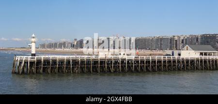 BLANKENBERGE, BELGIEN, 2. AUGUST 2021: Blick auf die Anlegestelle am Hafen von Blankenberge in Westflandern, mit dem Strand und den Wohnungen dahinter. Stockfoto