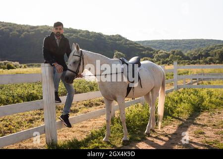 Der Mann ruht mit einem Pferd auf einer Ranch Stockfoto