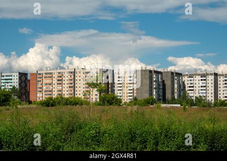 Blick auf typische Wohnhäuser und das vor ihnen stehende freie Grundstück an einem sonnigen Sommertag. Stockfoto