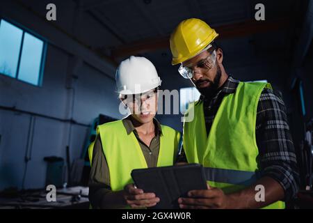 Porträt von Industrieinspektoren mit Tablet, die in Innenräumen in einer Metallwerkstatt eine allgemeine Überprüfung durchführen. Stockfoto