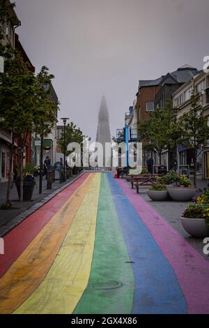 Vertikale Ansicht von Hallgrimskirkja, Kirche im Zentrum von Reykjavik bei nebligen Wetter mit Straße in Regenbogenfarben, die zu ihr führt. Stockfoto