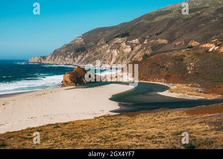 Am privat geführten Little Sur River Beach, Kalifornien, fließt zwischen pflanzenbewachsenen Sanddünen eine Mündung in den Pazifischen Ozean Stockfoto