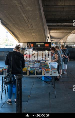 Leute, die an den Ständen des Southbank Centre Book Market am Queens Walk unter der Waterloo Bridge, London, England, Großbritannien, herumstöbern Stockfoto