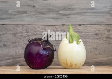 Nahaufnahme von zwei kleinen runden Auberginen auf dem Holzhintergrund. Stockfoto