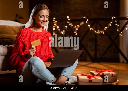 Weihnachtsgeschäfte. Lächelnde Dame mit Laptop und Kreditkarte Stockfoto