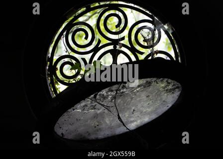 Der Blick durch ein rundes Fenster mit Bars in einem historischen Steingrab. Stockfoto