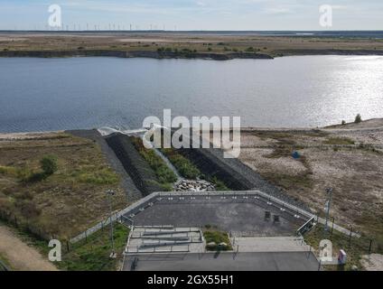 01. Oktober 2021, Brandenburg, Cottbus: Die Einlaufstruktur für das Wasser der aufstrebenden Cottbuser Ostsee, der ehemaligen Braunkohlemine Cottbus-Nord (Luftaufnahme mit Drohne). Auch die Landmasse darüber wird in den nächsten Jahren im Wasser verschwinden. Mitte April 2019 begann die Überschwemmung der ehemaligen Tagebaumine Cottbus-Nord. Das Energieunternehmen Lausitz Energie Bergbau AG (LEAG) lässt für das Hochwasser Wasser aus der Spree über den Hammergraben in das Tagebauloch fließen - rund 45 Millionen Kubikmeter pro Jahr sind geplant. Es wird berichtet, dass der riesige künstliche See einen Wassersurf hat Stockfoto