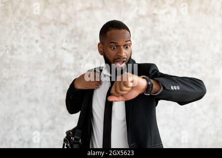 Verängstigte schwarze Mann ist zu spät für die Arbeit Blick auf Uhr Stockfoto