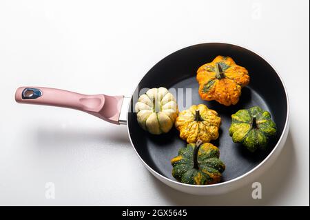 Dekorative Kürbisse auf einer Pfanne über einem weißen Küchentisch Hintergrund.Konzept von Thanksgiving Day, Halloween oder Herbsternte. Stockfoto