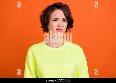 Foto von jungen braunen bob behaart unglücklich gestresst Frau schlechte Stimmung Grimasse isoliert auf orangen Hintergrund Stockfoto