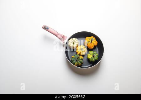 Dekorative Kürbisse auf einer Pfanne über einem weißen Küchentisch Hintergrund.Konzept von Thanksgiving Day, Halloween oder Herbsternte. Stockfoto