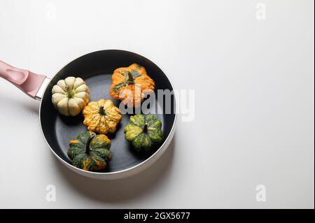 Dekorative Kürbisse auf einer Pfanne über einem weißen Küchentisch Hintergrund.Konzept von Thanksgiving Day, Halloween oder Herbsternte. Stockfoto