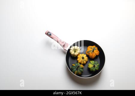 Dekorative Kürbisse auf einer Pfanne über einem weißen Küchentisch Hintergrund.Konzept von Thanksgiving Day, Halloween oder Herbsternte. Stockfoto