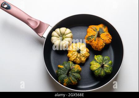 Dekorative Kürbisse auf einer Pfanne über einem weißen Küchentisch Hintergrund.Konzept von Thanksgiving Day, Halloween oder Herbsternte. Stockfoto