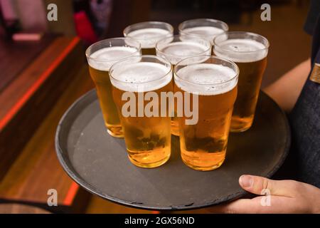 Der Kellner servierte Gläser kaltes Bier auf dem Tablett Stockfoto