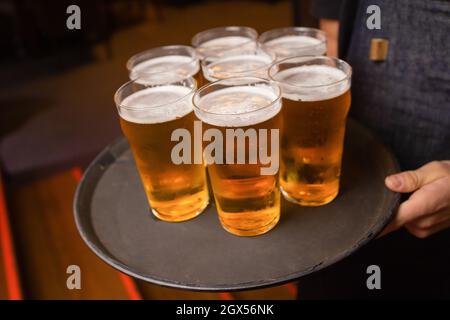 Der Kellner servierte Gläser kaltes Bier auf dem Tablett Stockfoto