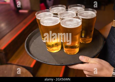 Der Kellner servierte Gläser kaltes Bier auf dem Tablett Stockfoto