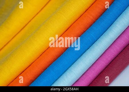 Ein Stapel mehrfarbiger, heller Leinenstoff, Nahaufnahme. Leinenhintergrund. Stoffstreifen Stockfoto