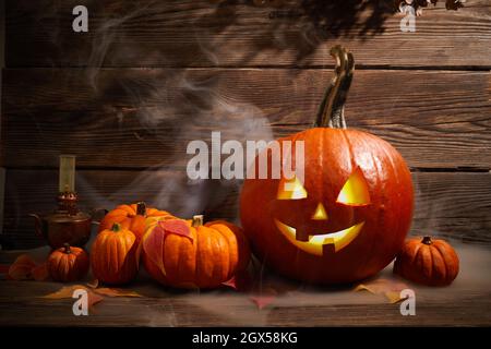 Halloween Kürbis Kopf Jack Laterne mit Rauch auf dunklem Holzhintergrund Stockfoto