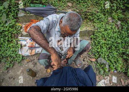 Barishal, Barishal, Bangladesch. Oktober 2021. Der Barbier schneidet einem alten Mann auf einem offenen Feld in Barishal, Bangladesch, Haare (Bildquelle: © Mustasinur Rahman Alvi/ZUMA Press Wire) Stockfoto