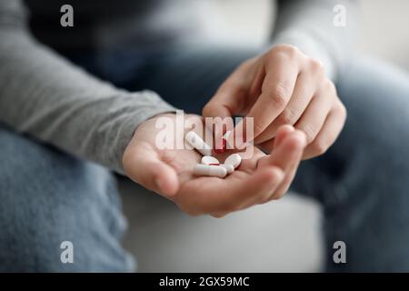 Unglückliche, tausendjährige kaukasische Frau, die an Depressionen leidet, hält Pillen aus nächster Nähe an der Hand Stockfoto