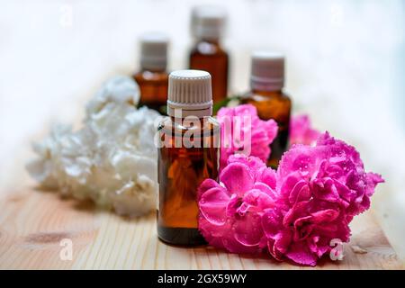 Natürliche handgemachte ätherische Öle mit Flaschen und frischen Blumen Aromatherapie Stockfoto