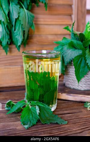 Heilender Kräutertee mit Brennnessel. Tee im Glas auf einem Holztisch. Volksheilmittel. Die Quelle von Vitaminen und Antioxidantien. Stockfoto