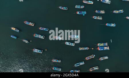 Viele farbige Fischerboote im Meer zwischen den blau-grünen Gewässern. Luftaufnahme von der Drohne. Nha Trang, Vietnam Stockfoto