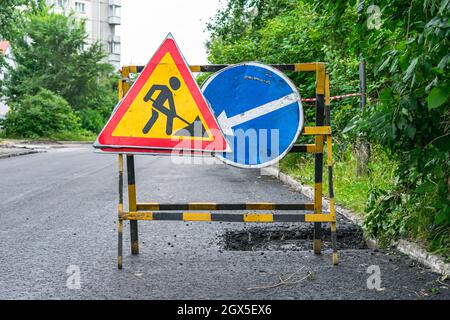 Straßenschilder, die vor Reparaturarbeiten und Verlegung von neuem Asphalt warnen Stockfoto