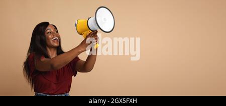 Emotionale schwarze Frau mit Megaphon, das etwas laut sagt Stockfoto