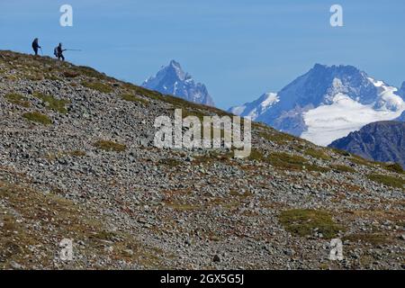 CHAMROUSSE, FRANKREICH, 23. September 2021 : ein paar Wanderer auf den Pisten, mit hohem schneebedeckten Gipfel im Hintergrund Stockfoto