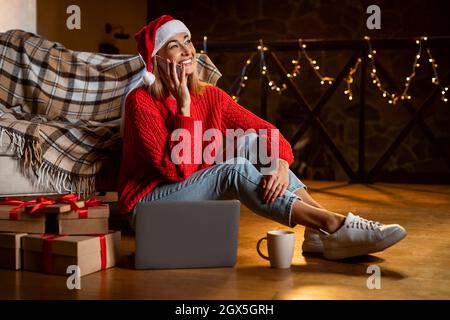 Glückliche Frau In Weihnachtsmütze Im Telefonat Stockfoto