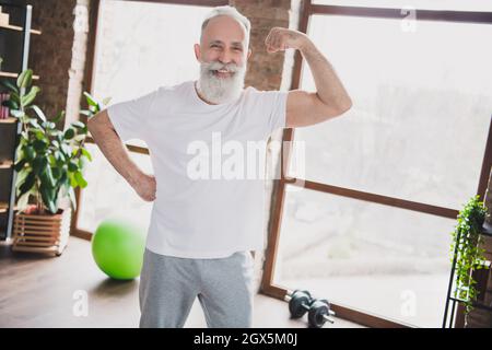 Foto von positiv lächelnd fröhlich hübsch sportlich reifen Mann Training zu Hause Haus zeigt Muskeln Stockfoto