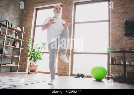 Foto in voller Größe von gutaussehenden konzentrierten gut aussehenden positiven reifen Mann Training zu Hause tun Herz Stockfoto