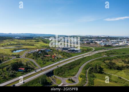 Luftaufnahme von asphaltierten Straßen und Kreisverkehr in grünem Tal in der Nähe von Vorort gegen wolkenlosen blauen Himmel im Sommer. Stockfoto
