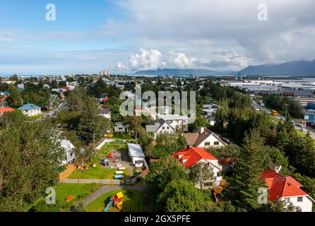 Drohnenblick auf Hütten und Spielplatz inmitten üppiger grüner Bäume gegen den wolkigen blauen Himmel am Sommertag in der Küstenstadt. Stockfoto