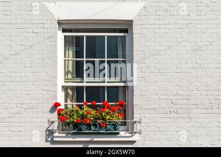 Schiebefenster mit Blumenkästen an einer weiß gestrichenen Ziegelwand. Stockfoto