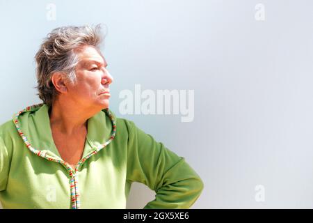 Profilportrait einer älteren Frau mit kurzen grauen Haaren, die auf weißem Hintergrund wütend aussass. Foto mit Copyspace Stockfoto