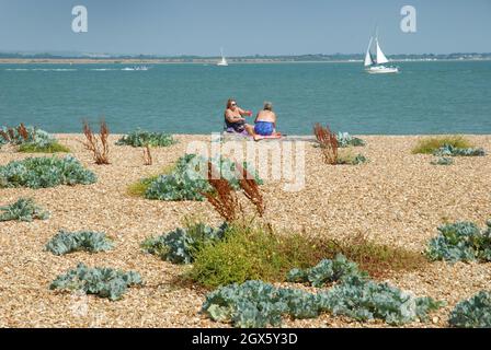 Zwei Frauen saßen am Strand, Calshot Beach, Calshot, Hampshire, Großbritannien. Stockfoto