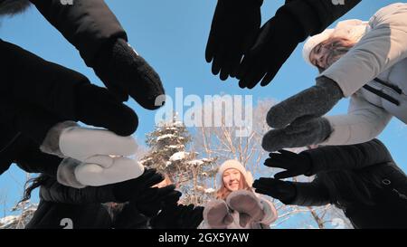 Freunde an einem Wintertag verbinden sich mit Fäustlingen im Kreis. Stockfoto