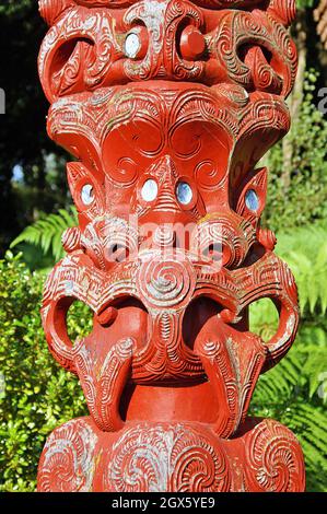 Ein roter hölzerner Maori-Tekoteko mit hervorstehenden Zungen und Augen von Paua-Muscheln steht 2005 in Rotorua, Neuseeland. Das Erzählen von Geschichten durch Holzhandwerk ist eine Tradition der Maori, wobei jeder Tekoteko eine einzigartige Geschichte erzählt. Stockfoto