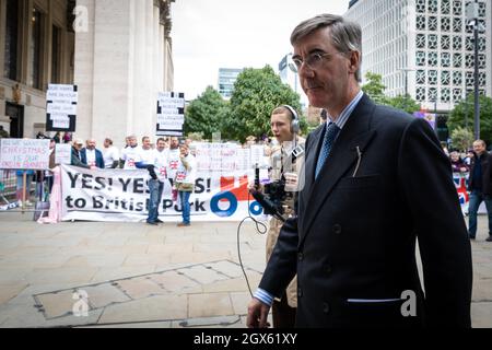 Manchester, Großbritannien. Oktober 2021. Jacob Rees-Mogg geht auf die Konferenz der Konservativen Partei zu, vorbei an Schweinezüchtern, die außerhalb der Veranstaltung protestieren. Britische Bauern protestieren gegen die Tory Party aufgrund der Auswirkungen des Brexit, der zu Fachkräftemangel und Einschränkungen geführt hat. ÊAndy Barton/Alamy Live News Credit: Andy Barton/Alamy Live News Stockfoto