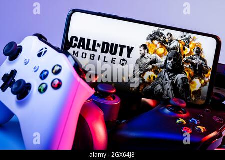 Ein Smartphone mit dem Rahmen von Call of Duty auf dem Stapel der Gamepads. Stockfoto