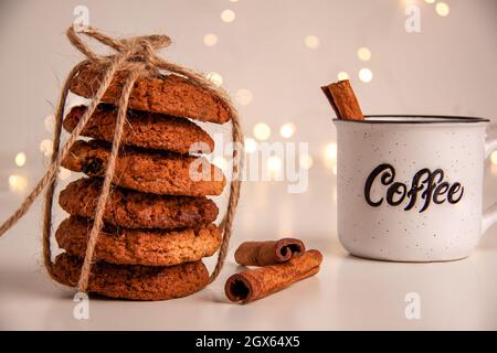 Nahaufnahme von Haferflocken in einem Stapel mit braunen Faden Kaffeetasse und Zimtstangen auf hellem Hintergrund mit Bokeh gebunden. Sweet Food-Konzept mit Stockfoto