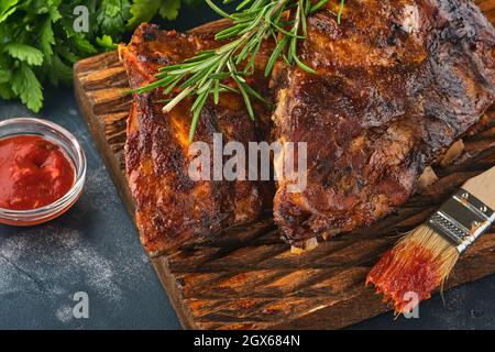 Gegrillte und geräucherte Schweineribs mit Barbeque-Sauce auf einem alten Holzschneidebrett. Leckerer Snack bis Bier. Nahaufnahme des Bildes. Stockfoto