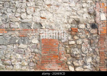 Steinmauer. Der rote Ziegel und der große weiße Stein sind in einer anderen Reihenfolge gestapelt. Fragment einer alten Burg Stockfoto