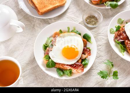 Offenes Sandwich mit Spiegeleiern, Speck und Gemüseblättern. Nahaufnahme Stockfoto