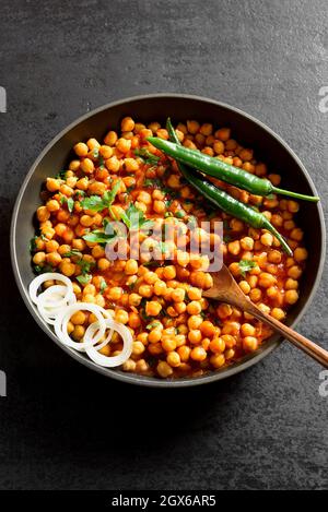 Knusprig geröstete Kichererbsen. Gericht im indischen Stil über schwarzem Stein Hintergrund. Vegetarisches veganes Food Konzept. Stockfoto