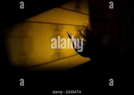 Silhouette einer Frau, verzweifelt, mit einem Arm in der Luft und fliegenden Haaren. Mystery Night Scene. Stockfoto